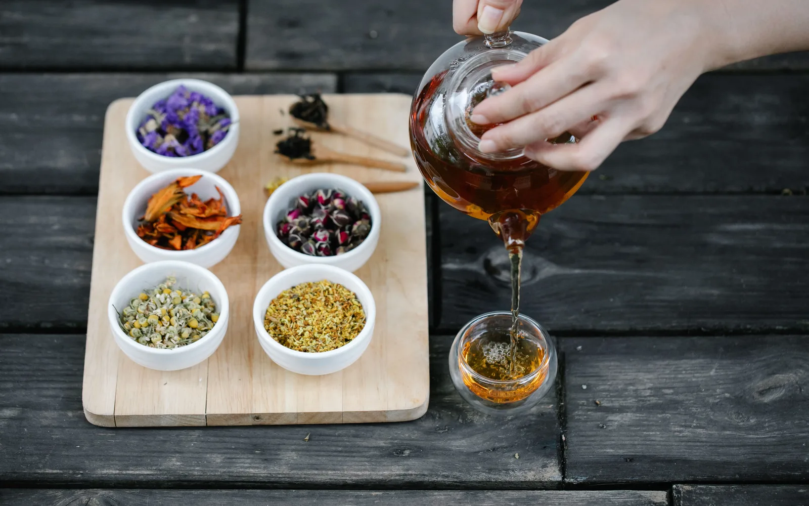 Tisane versée près de bols de plantes séchées